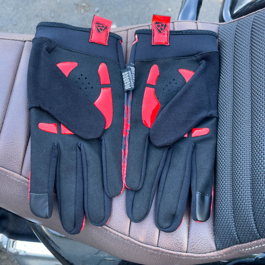 Red motorcycle glove’s padded palms on motorcycle seat. Menace Mitts.