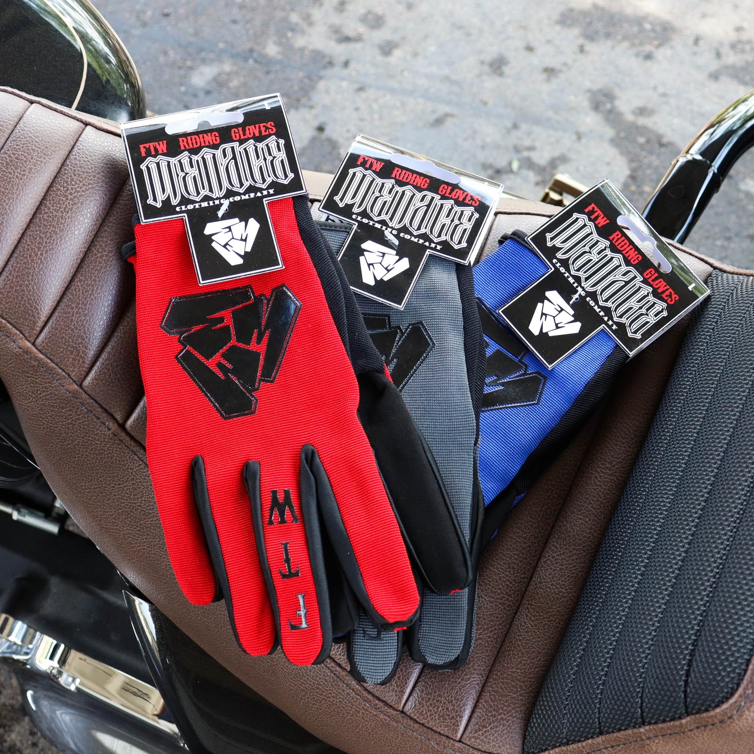 Menace Clothing’s red, gray, and blue FTW motorcycle gloves on motorcycle seat.