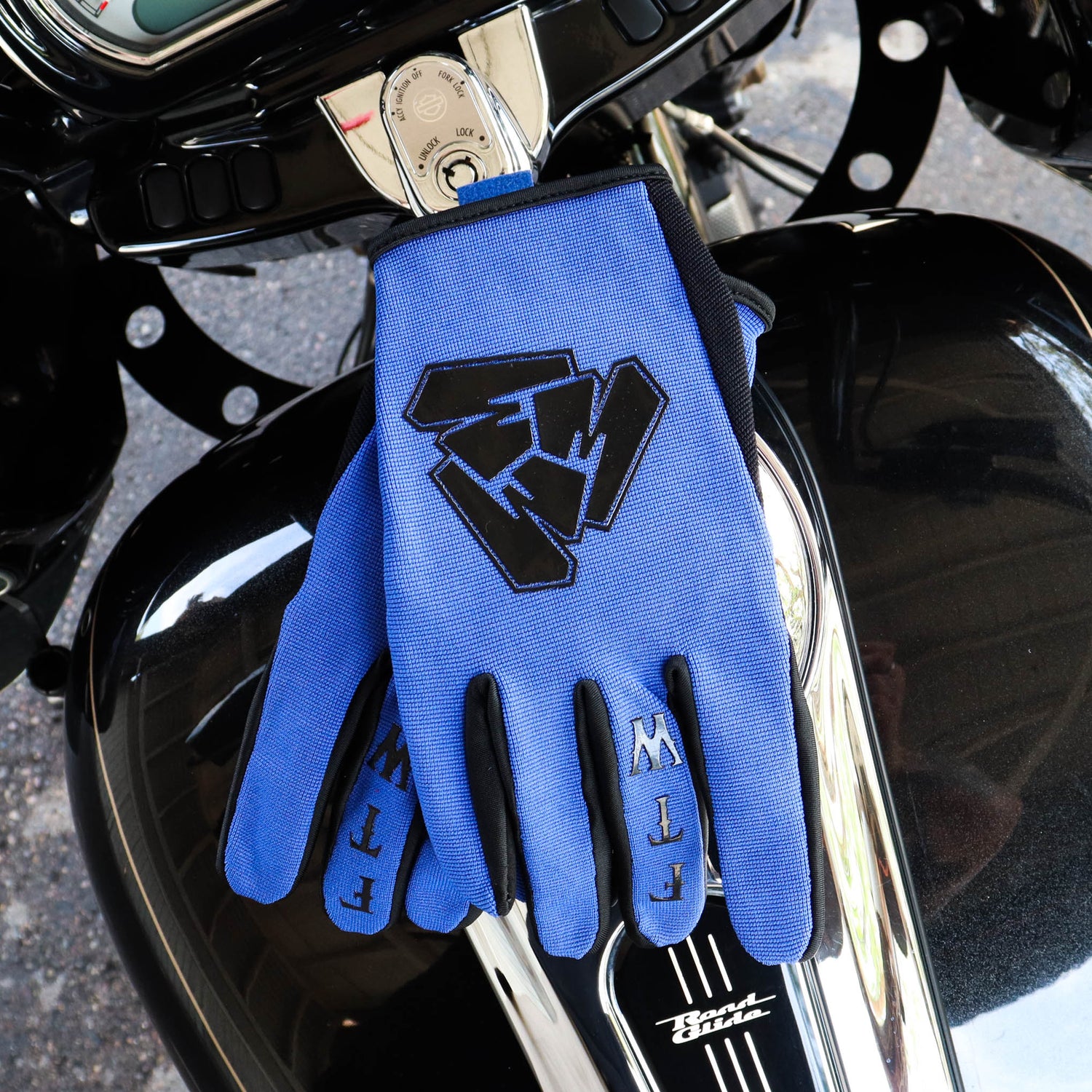 Menace Clothing’s blue FTW motorcycle gloves on motorcycle gas tank