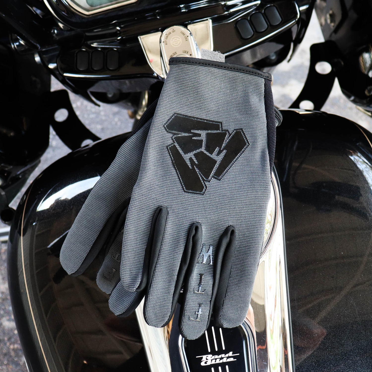 Menace Clothing’s gray FTW motorcycle gloves on motorcycle gas tank