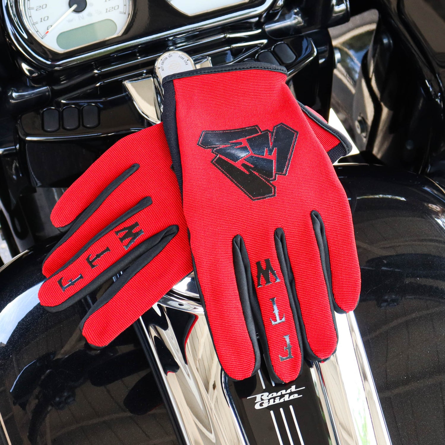 Menace Clothing’s red FTW motorcycle gloves on motorcycle gas tank.