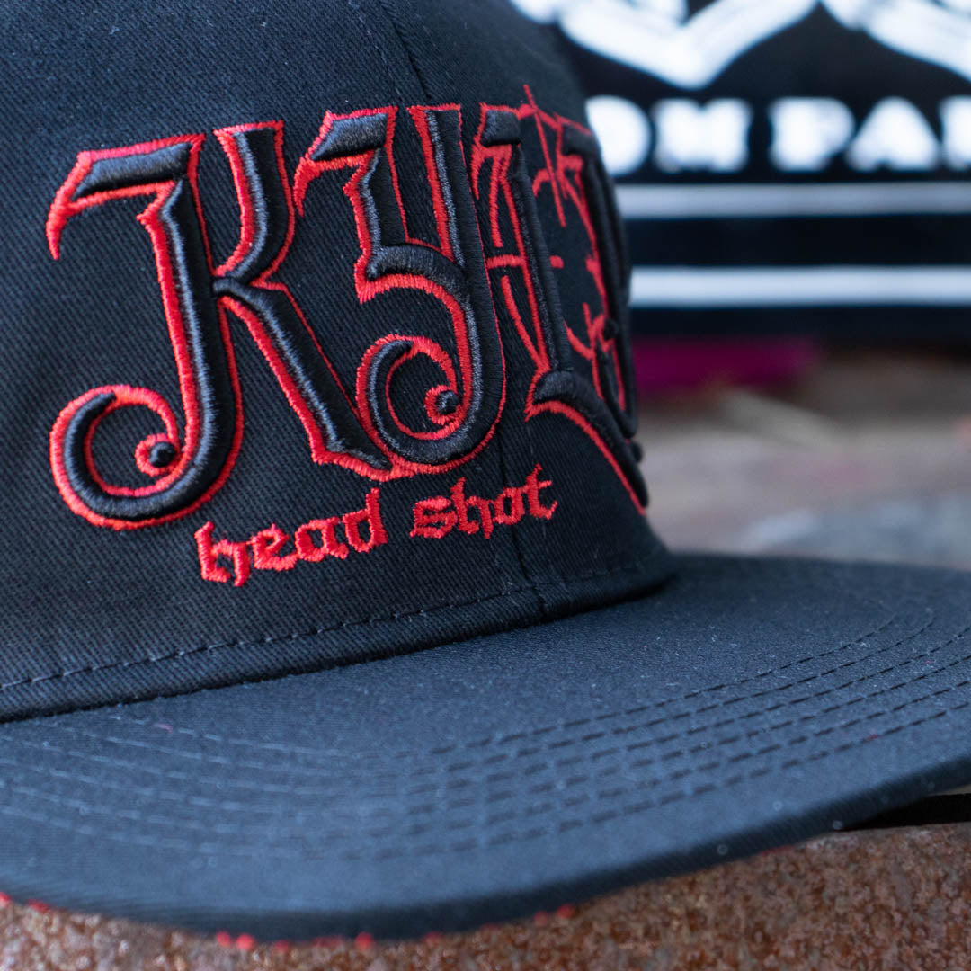Embroidered close up of front of Menace Clothing black and red baseball hat saying KYLP and Head Shot. 