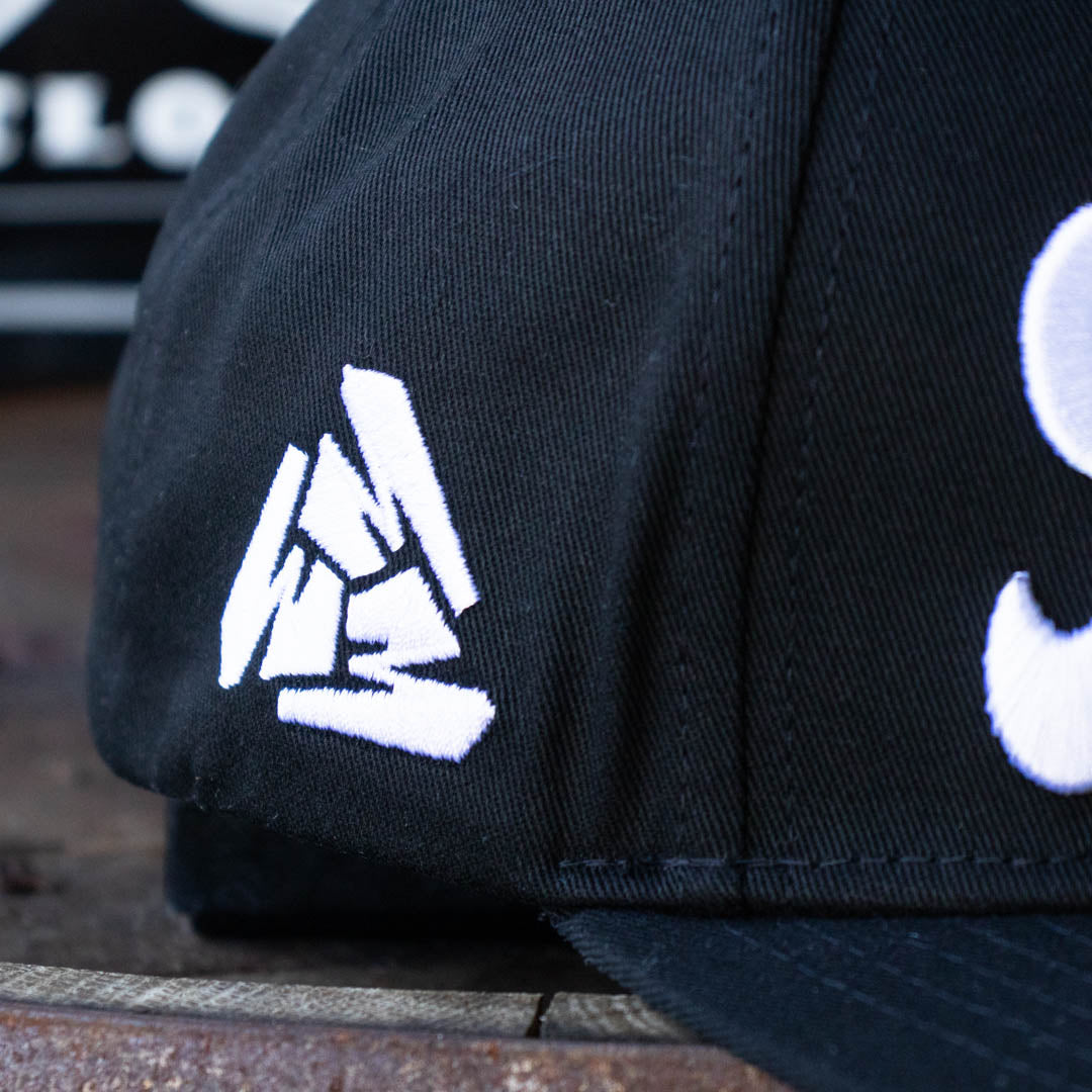 Close up of right side of Menace Clothing black baseball hat with white embroidered Menace Tri M logo. 